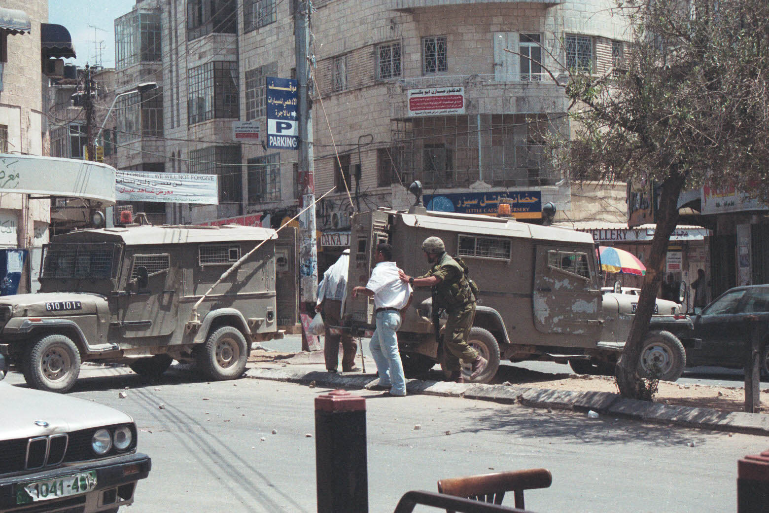 Scontri con le forze di occupazione sioniste nel centro di Ramallah durante la seconda Intifada: un soldato israeliano sta arrestando un uomo (Yousef al-Qutub, 2000-2002) - The Palestinian Museum Digital Archive